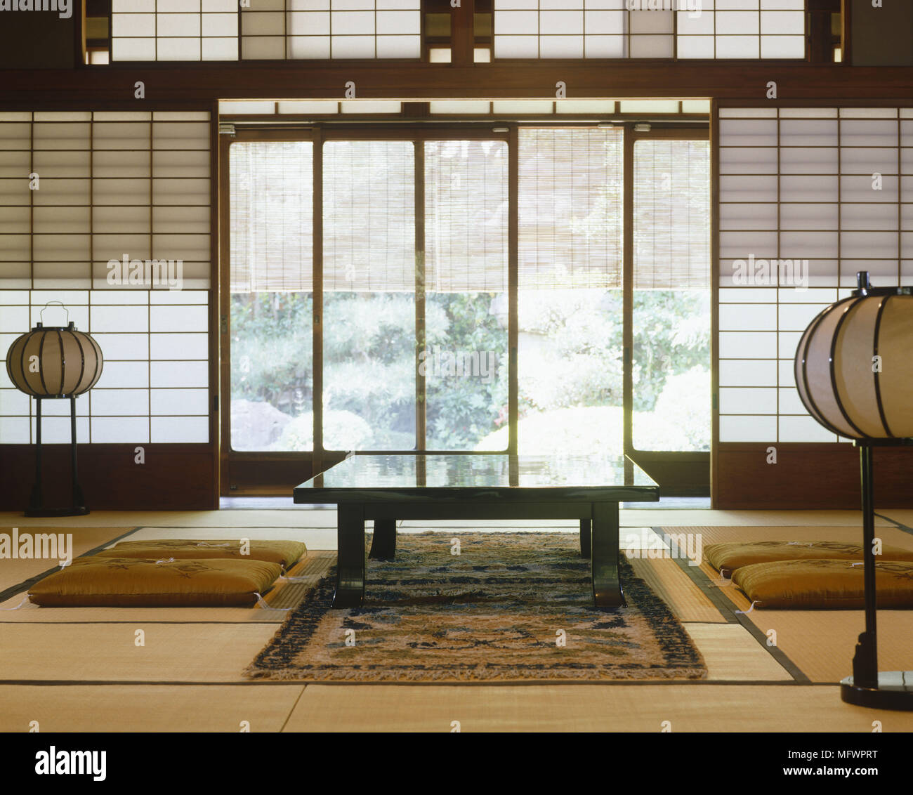 Mesa de comedor de estilo japonés con cojín en la habitación con lámparas  orientales y persianas de papel japonés Fotografía de stock - Alamy