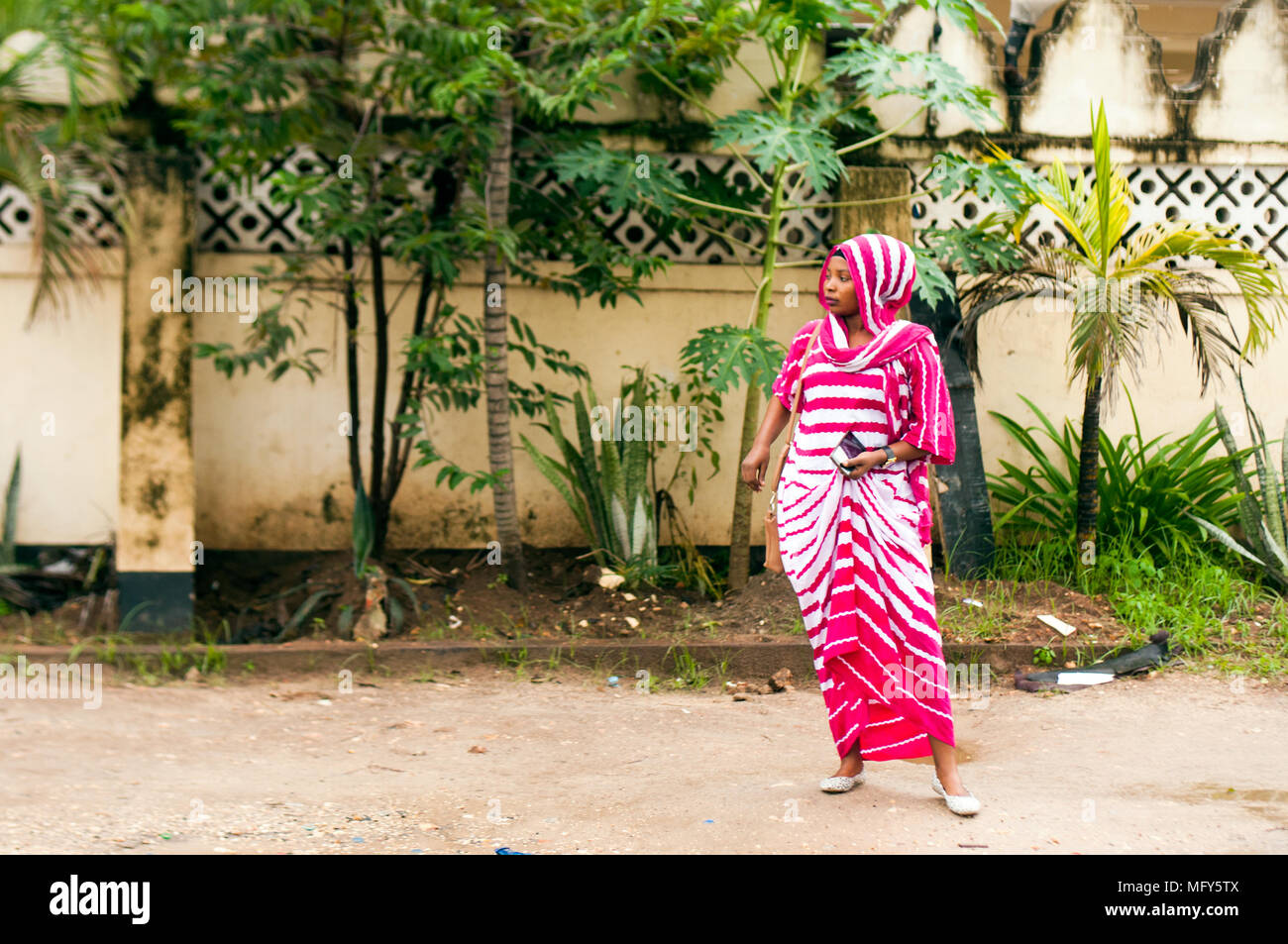 Una mujer esperando el autobús en la Avenida Kimeri Msasani, Dar-es-Salaam Foto de stock