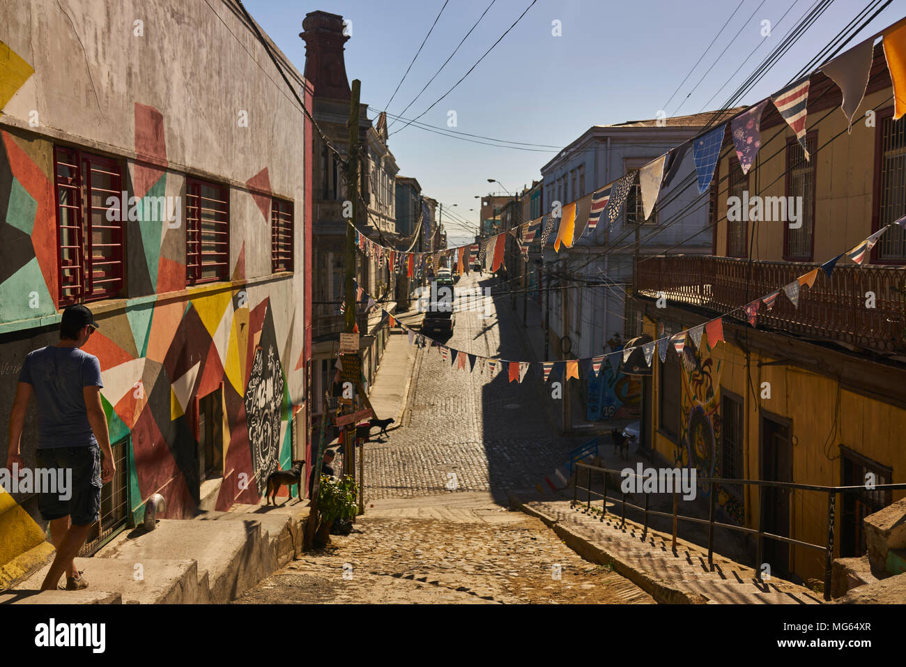 Downhill pintorescas calles que conducen al océano en Valparaíso, Chile. La arquitectura colonial y banners crear una atmósfera vibrante. Foto de stock