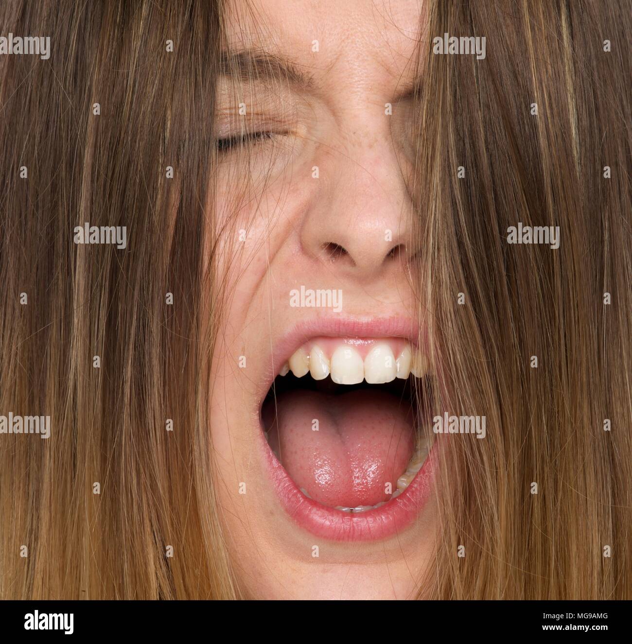 Mujer joven gritando con la boca abierta. Foto de stock