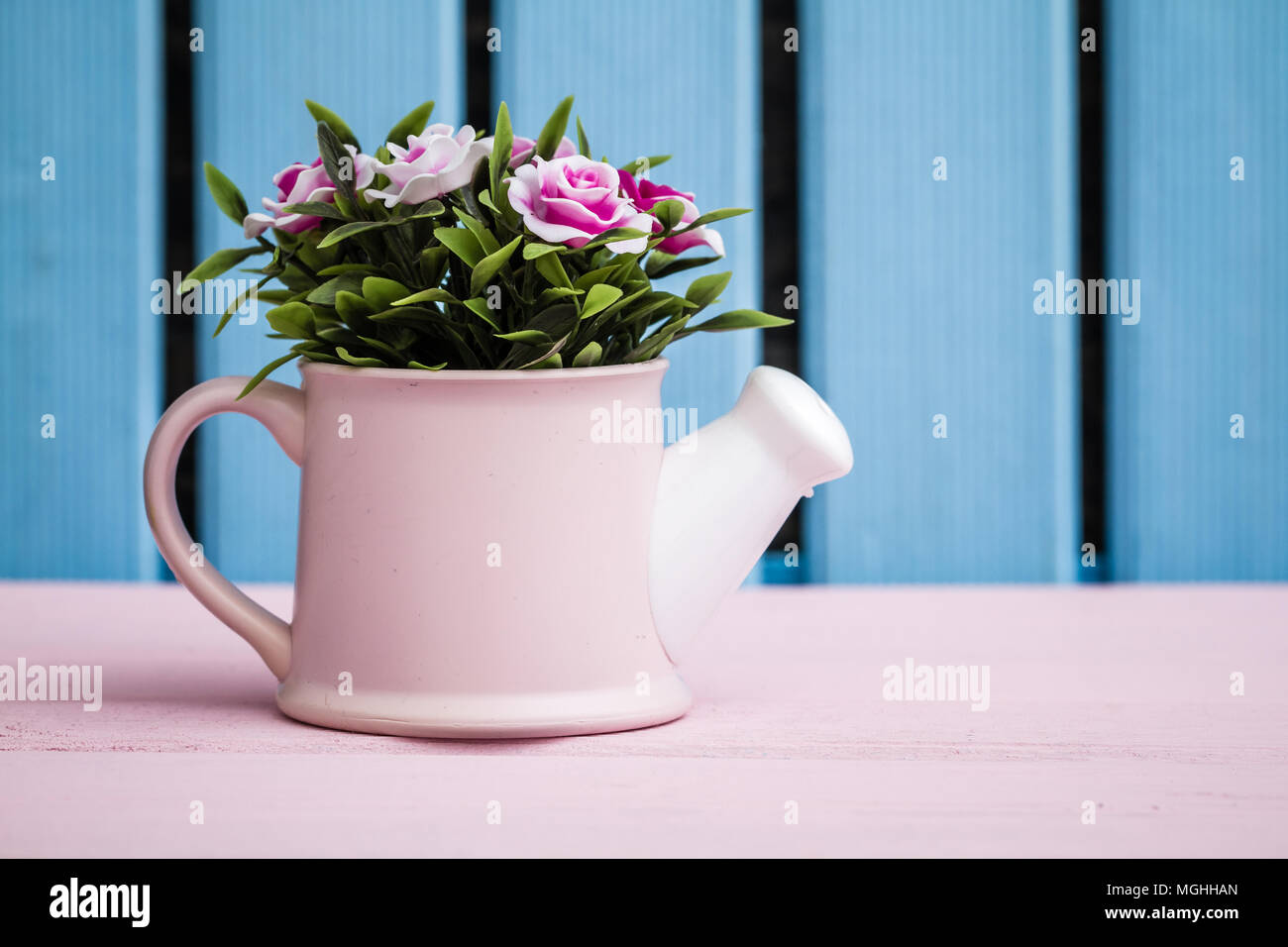 Coloridas flores artificiales en Macetas decorativas sobre fondo de madera  azul Fotografía de stock - Alamy