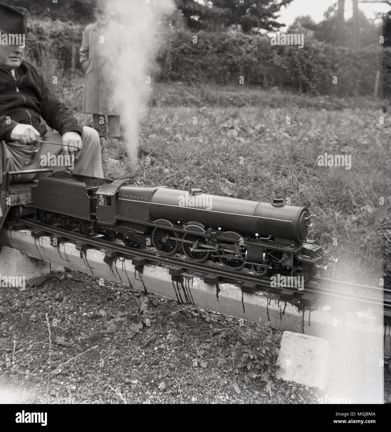 1950s, históricos, macho adulto amteur entusiastas de ferrocarril con un tren de vapor en un trenecito, Inglaterra, Reino Unido. Foto de stock
