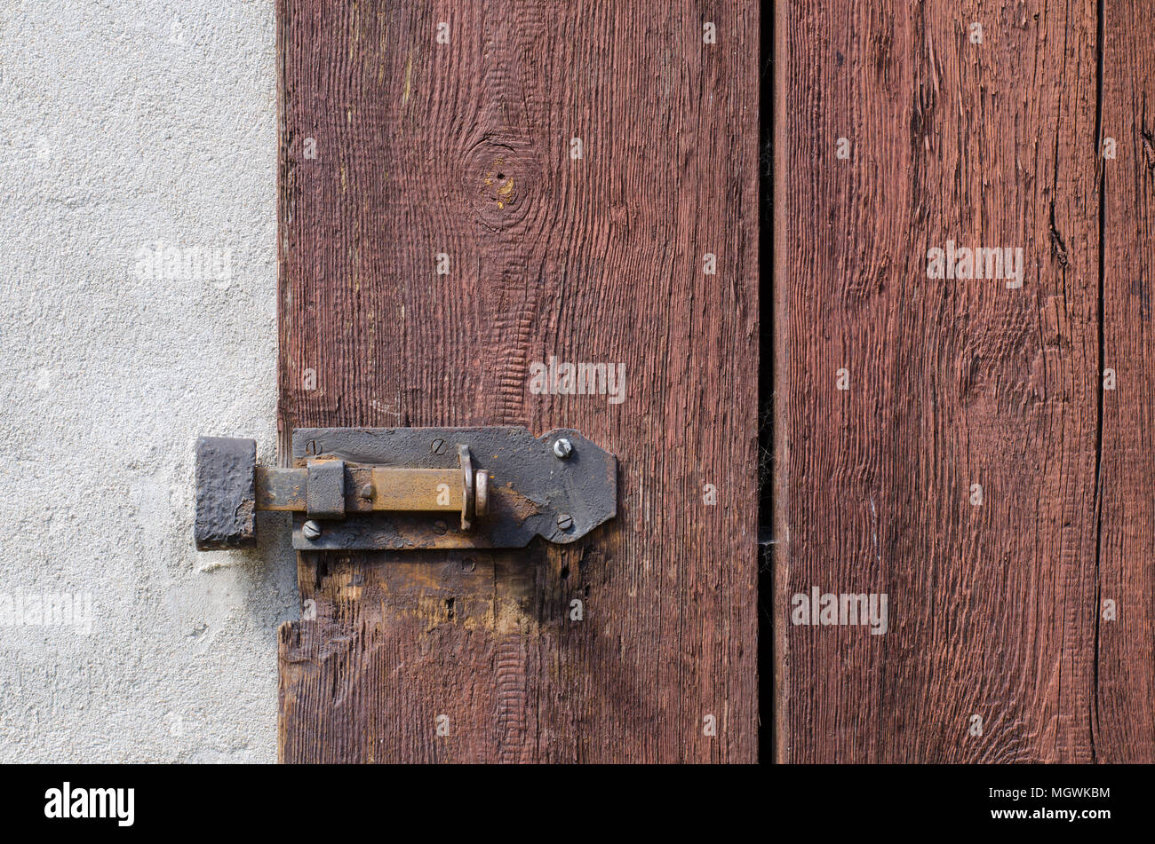 Primer plano de un antiguo mecanismo de bloqueo de la puerta de madera en el muro de cemento Foto de stock