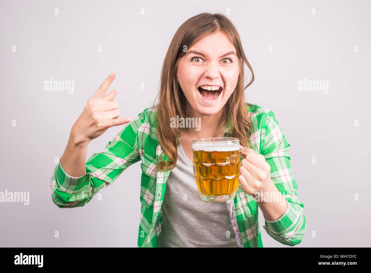 Joven alegre sosteniendo una jarra de cerveza llena de cerveza y sonriendo sobre fondo blanco. Foto de stock