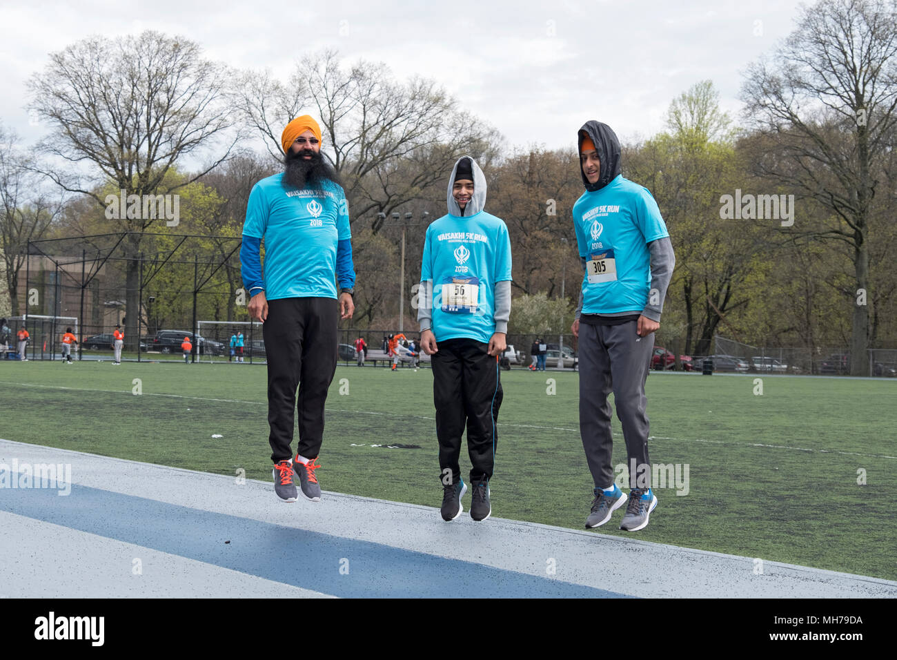 Tres hombres Sikh saltando de arriba a abajo como un calentamiento antes de la Vaisakhi 5k run en el Victory Field, Woodhaven, Queens, Nueva York. Foto de stock