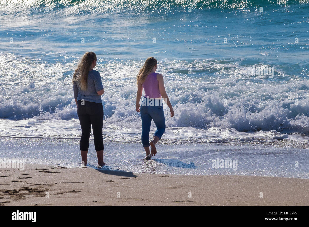 Dos niñas remando en el mar, en la playa Fistral en Newquay en Cornualles. Foto de stock