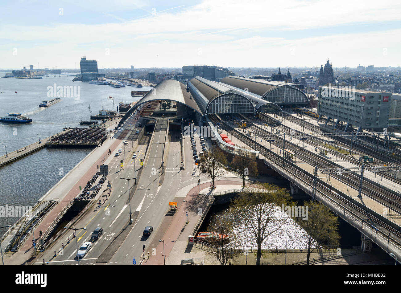 Vista aérea de la ciudad y de la Estación Central (Centraal Station) mostrando soluciones de movilidad (los trenes de los ferrocarriles, los automóviles en las calles, los transbordadores por vías navegables), Amsterdam Foto de stock