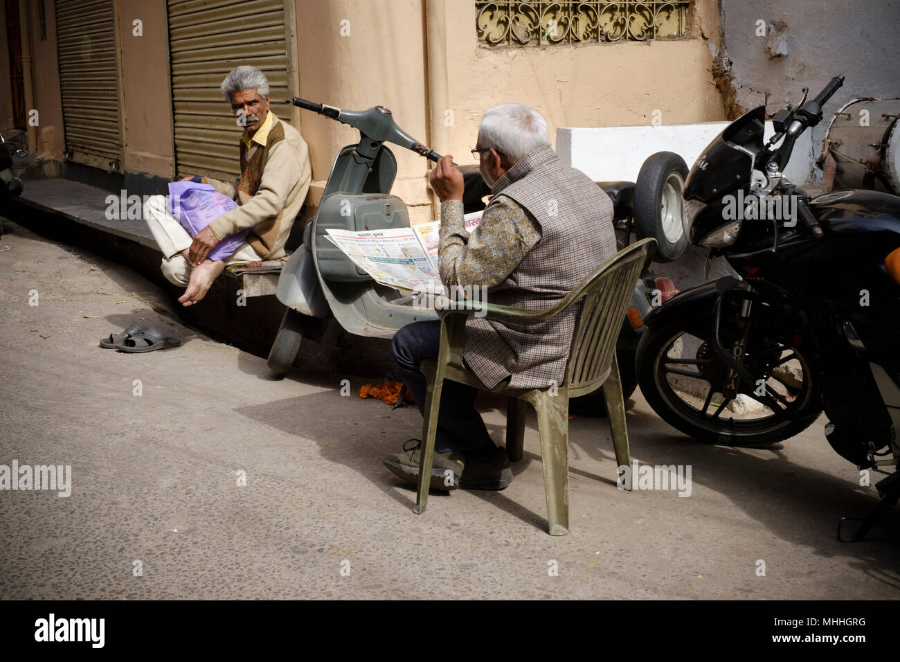 Dos hombres y un niño hablando como la vida pasa alrededor en la esquina de una calle. Udaipur, también conocida como la ciudad de Lagos, la Venecia de Oriente, es la capital histórica del reino de Mewar, Rajasthan. Foto de stock