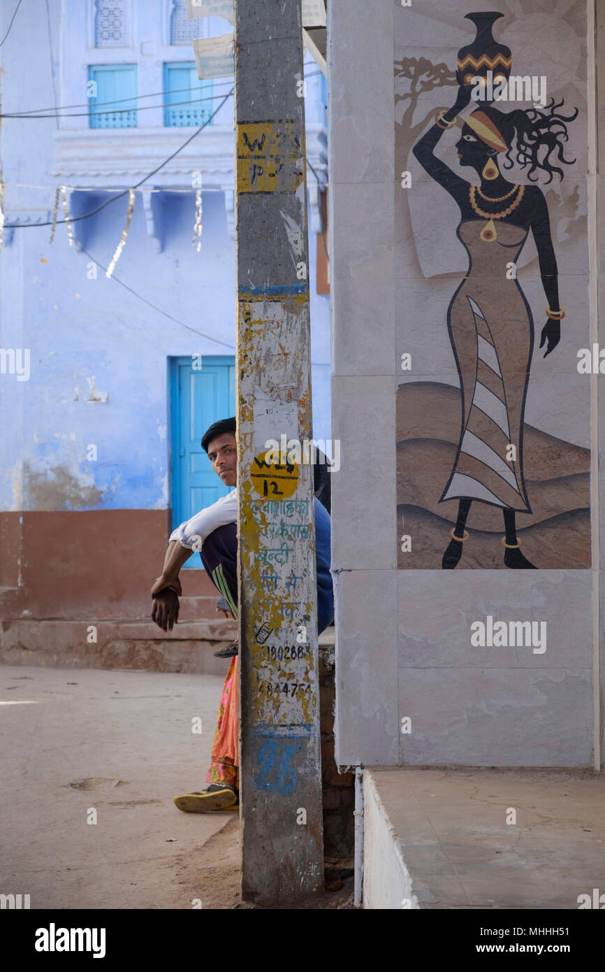 Sentada sobre un paso con el mural de la mujer con un cántaro sobre su cabeza. Foto de stock