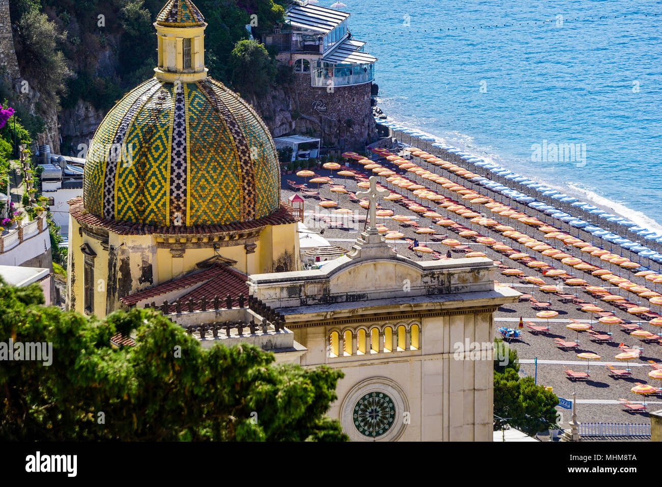 Primer plano de la Chiesa di Santa Maria Assunta en Positano, Amalfi Coast, Italia desde arriba con sombrillas en segundo plano. Foto de stock