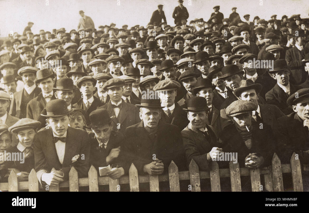 Una multitud de hombres bien vestido espectadores observar las actuaciones desde detrás de una valla, tal vez en un evento deportivo en el noreste de Inglaterra. Fecha: c.1910s Foto de stock