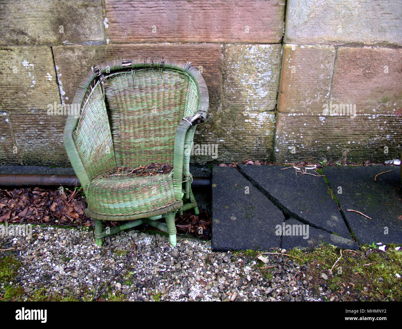 Desvencijado jardín roto Lloyd Loom silla con adoquines rotos nadie copyspace desordenados. Foto de stock
