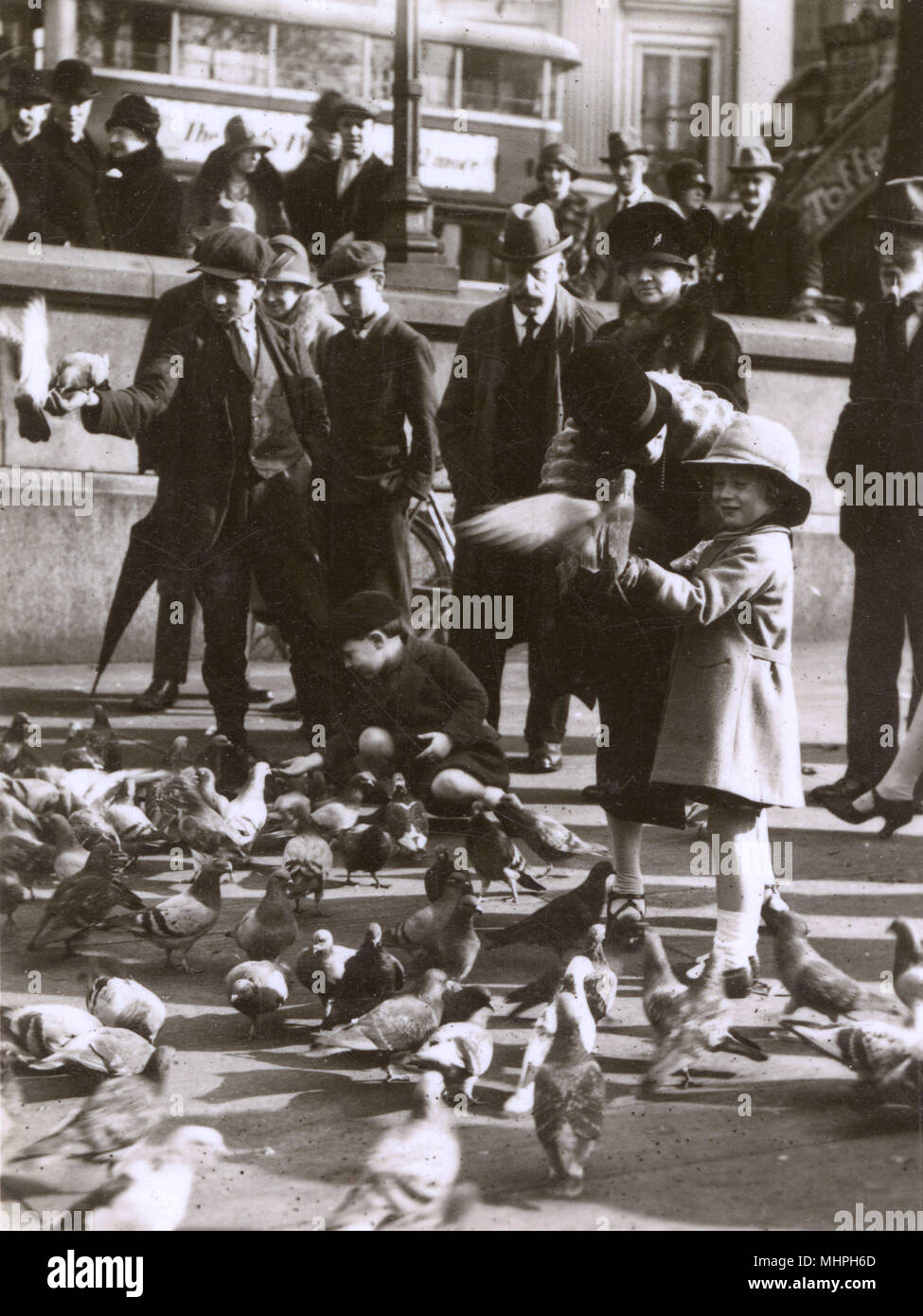 La gente alimentando a las palomas en Trafalgar Square, Londres. Fecha: circa 1930 Foto de stock
