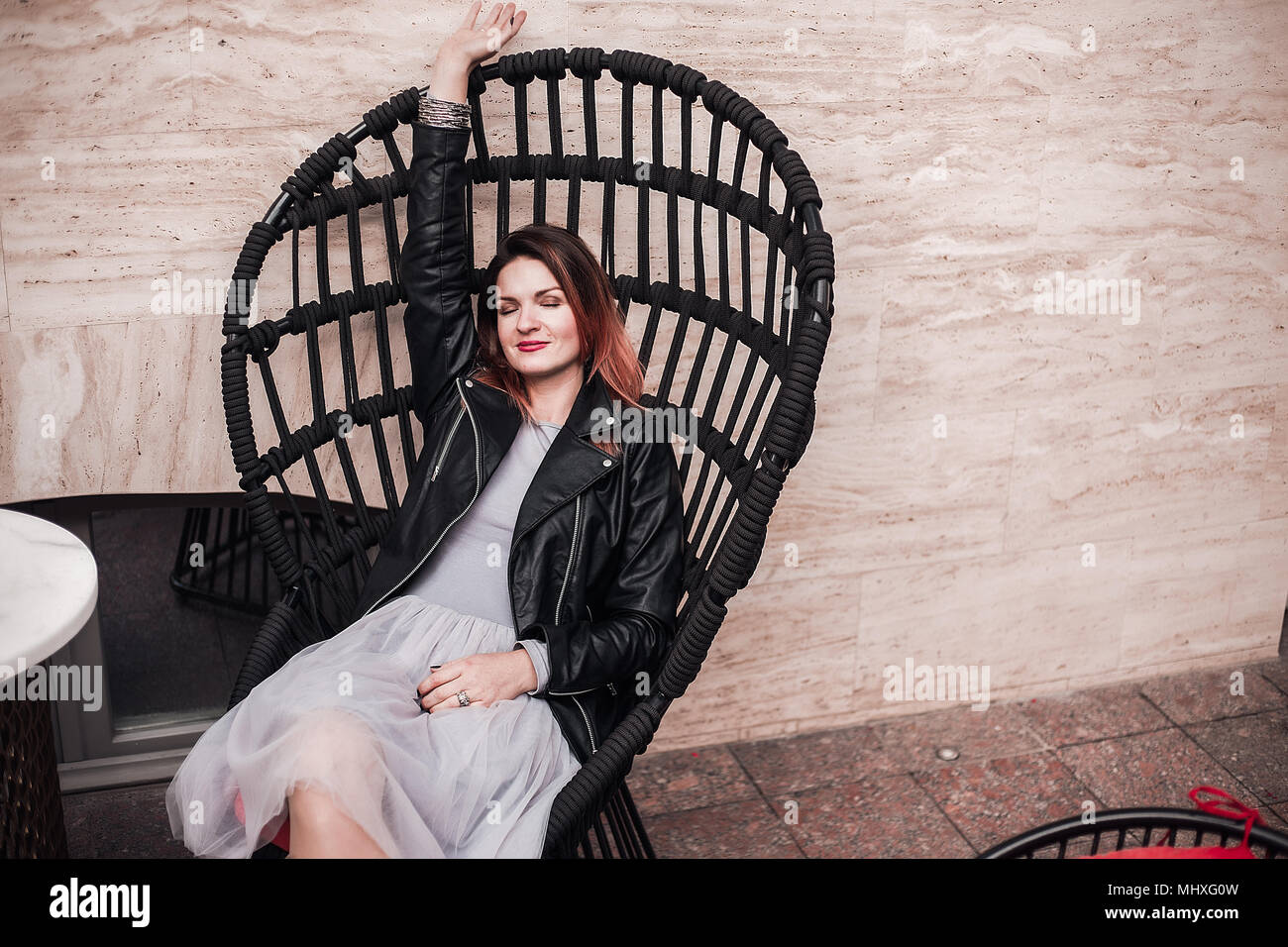 Retrato de mujer sentada en una silla con el brazo levantado Foto de stock