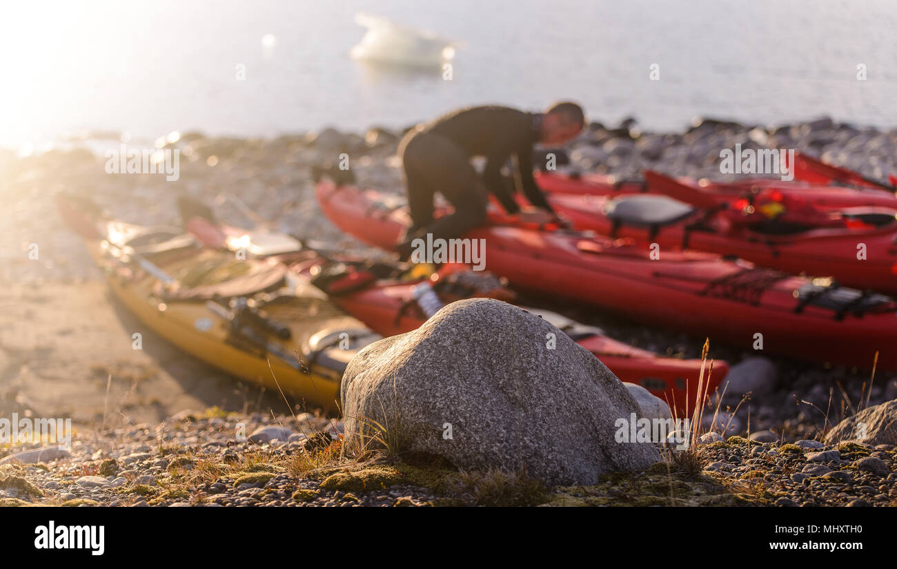 El hombre la preparación de kayak de mar, sobre la playa, Narsaq, Kitaa, Groenlandia Foto de stock