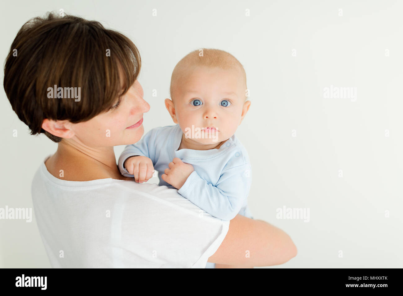 Madre sosteniendo Baby Boy, mirando por encima del hombro a la cámara Foto de stock