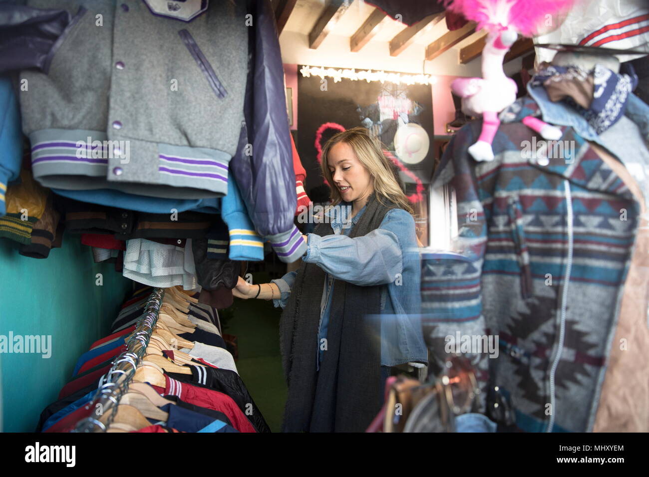 Mujer joven mostrando Vintage ropas en thrift store Foto de stock