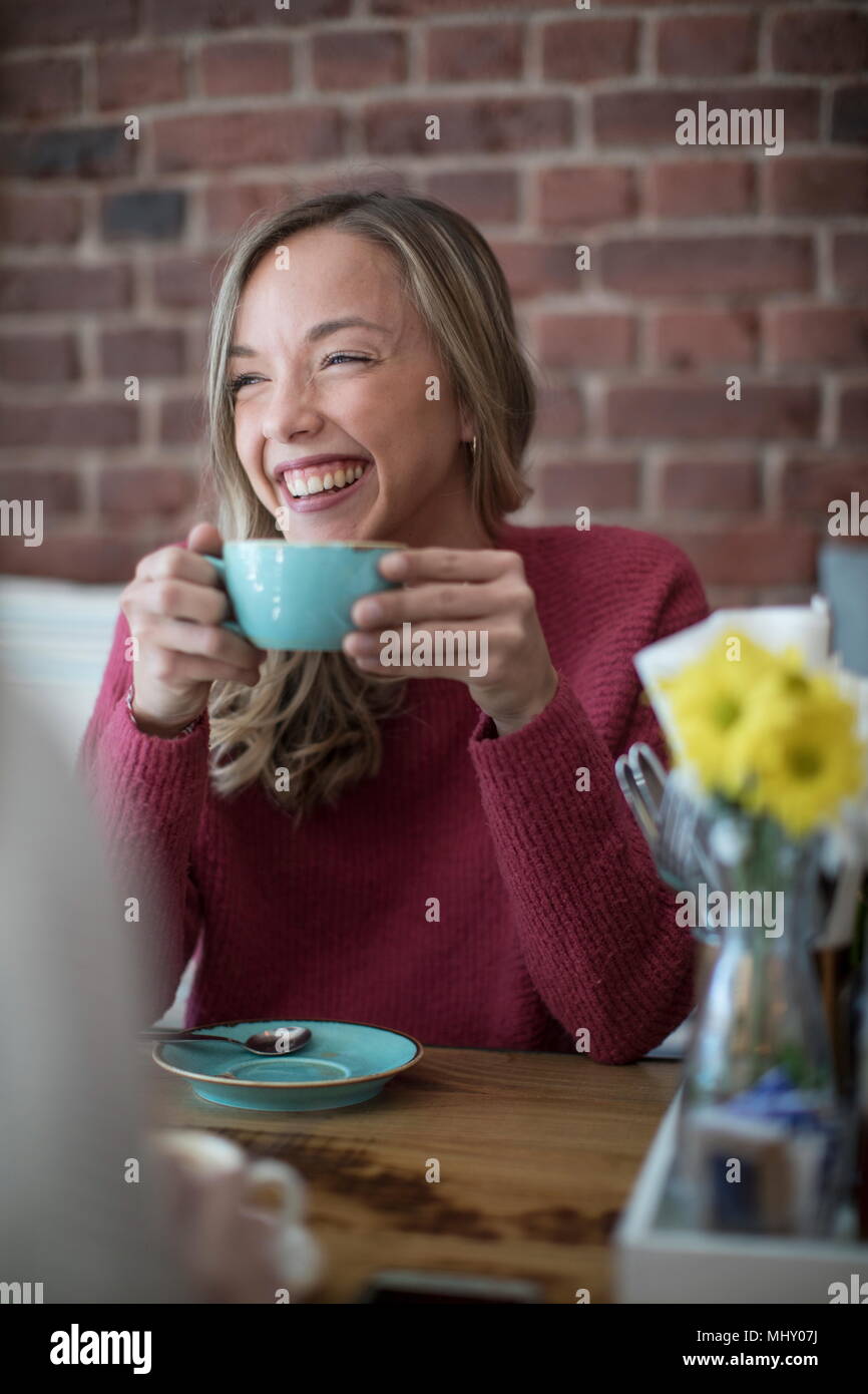 Mujer sentada en el café, beber café, sonriendo Foto de stock