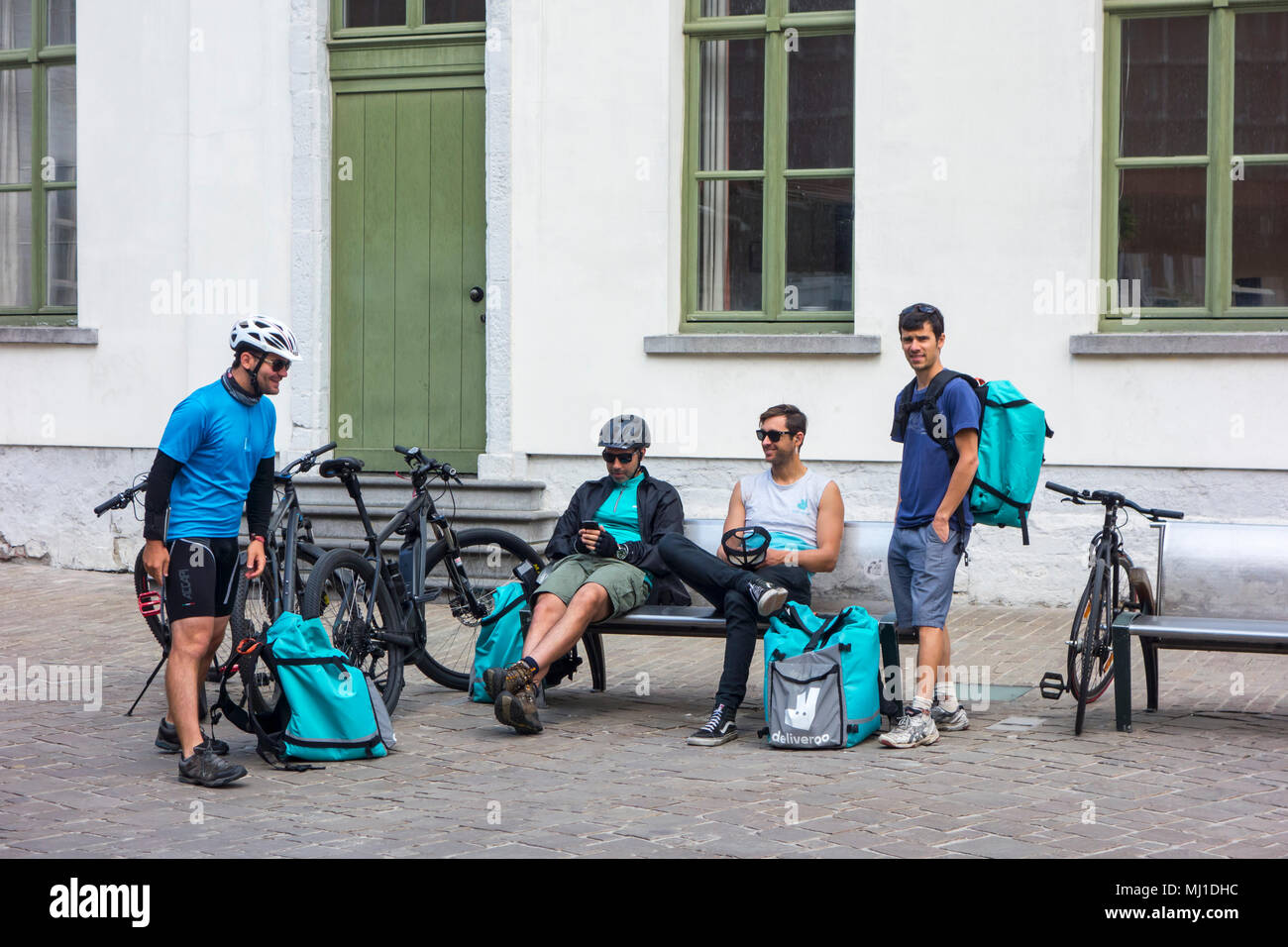 Mensajeros en bicicleta - trabajando para Deliveroo, empresa de distribución de alimentos en línea británica - tomando un descanso en el centro de la ciudad. Foto de stock