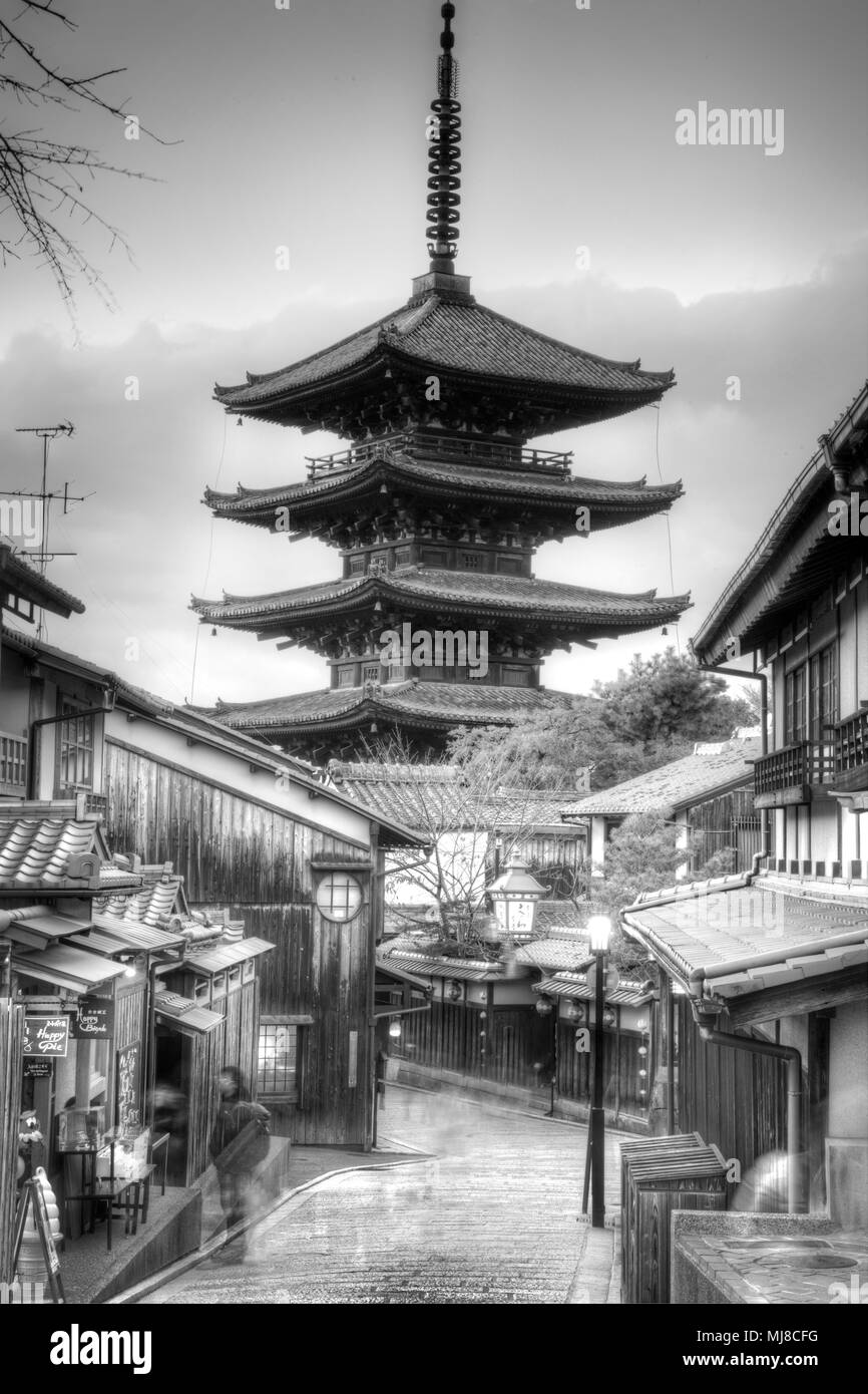 Calle bordeada de edificios tradicionales con altos pagoda de madera del templo budista en la distancia. Foto de stock