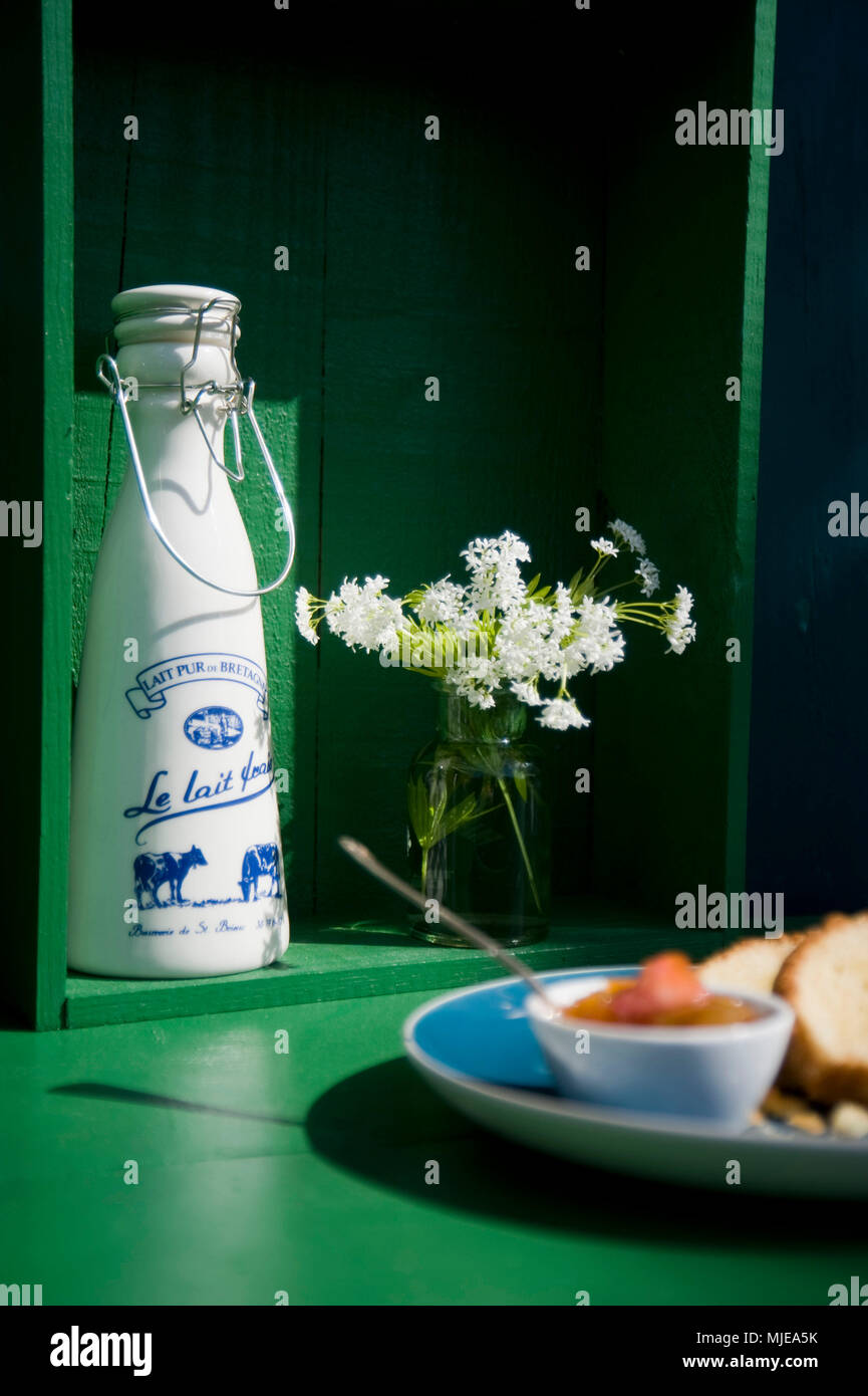 Breton jarra de leche, flores blancas, torta con mermelada Foto de stock