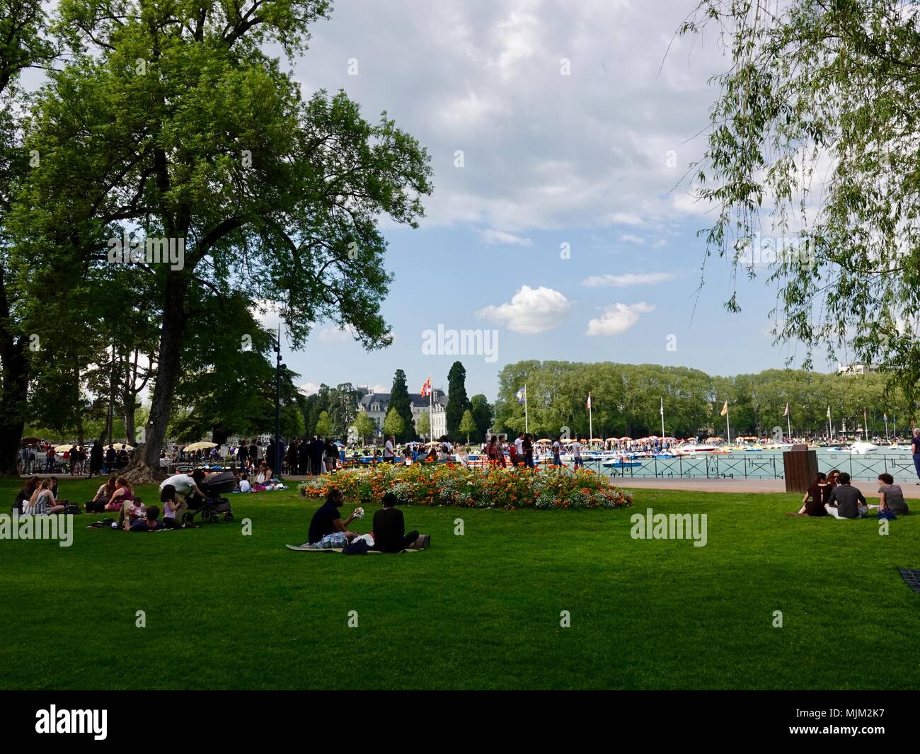 Las personas relajarse en el césped con picnic en un parque junto al lago en una agradable tarde de sábado en Annecy, Francia Foto de stock