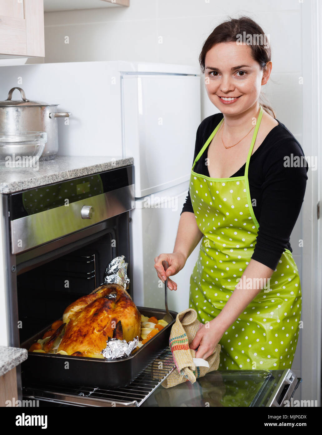 Sonriente mujer alegre gallo asar para la cena en la cocina microondas  Fotografía de stock - Alamy