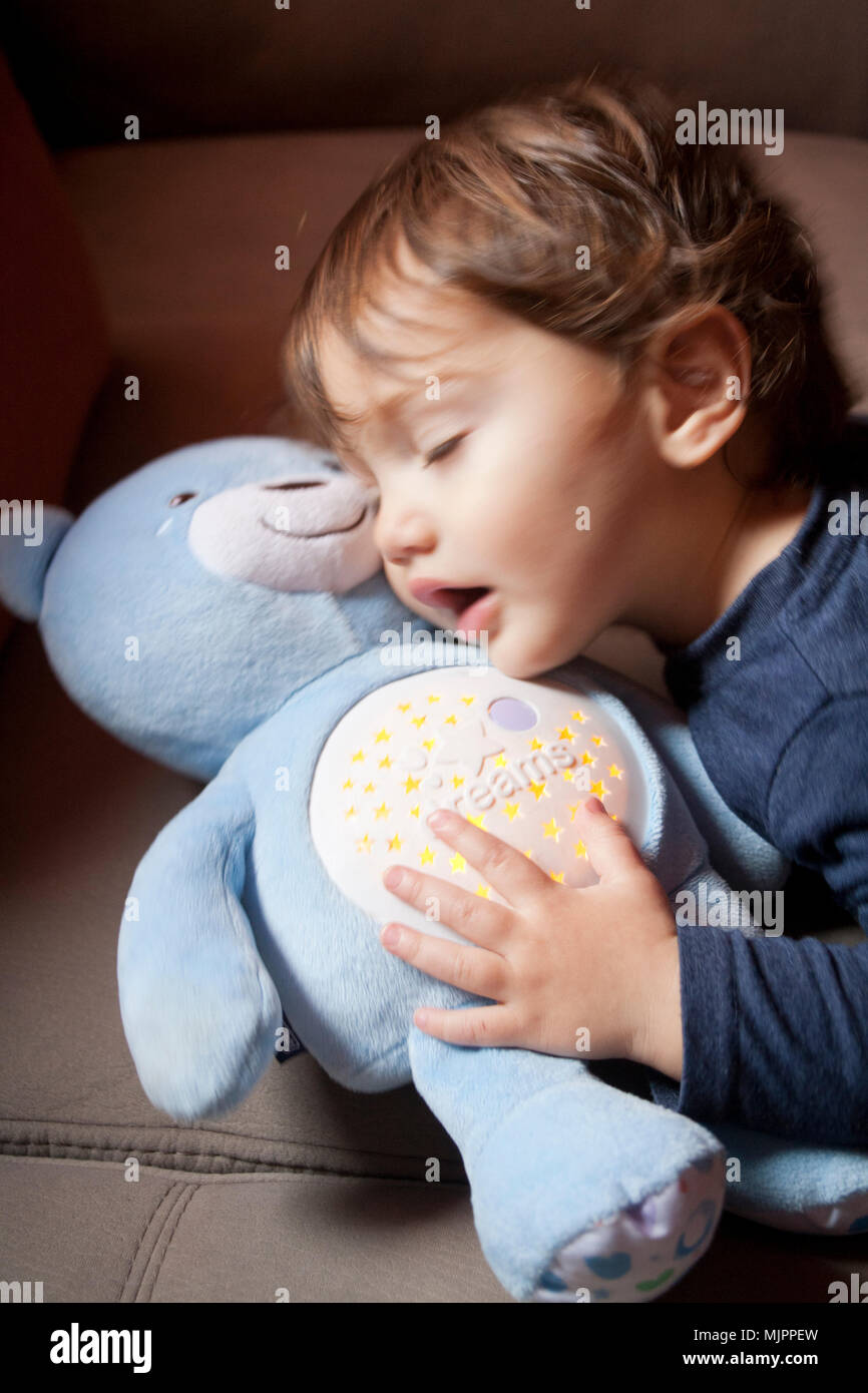Dos años niño abrazando a un oso de peluche plush Foto de stock