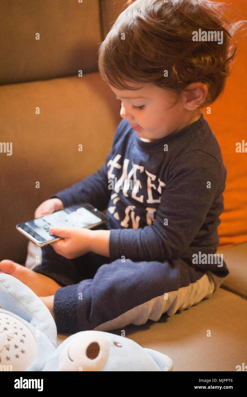 Niño de dos años jugando con un IPhone Foto de stock
