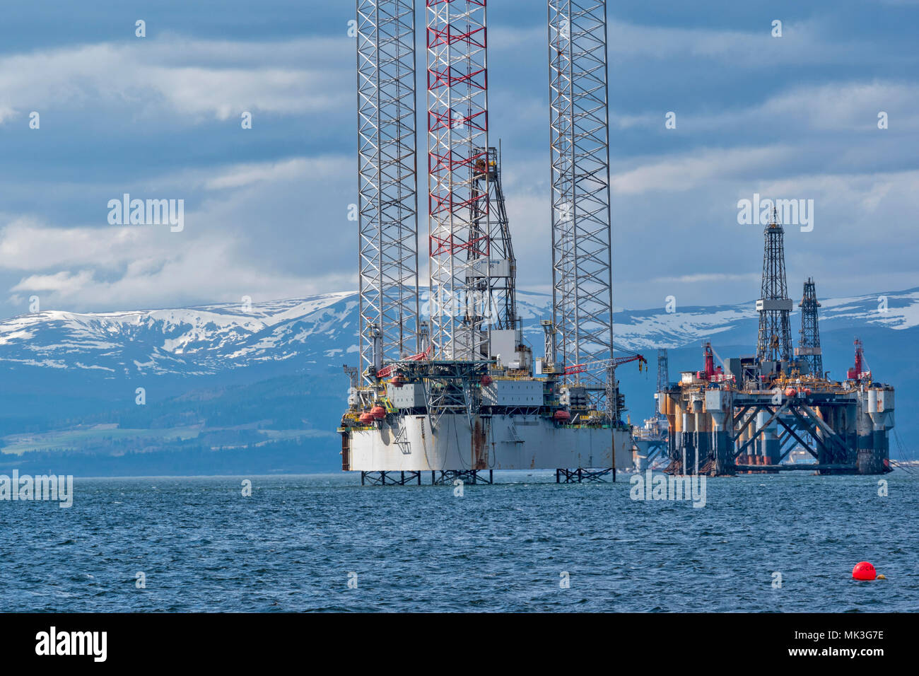 CROMARTY FIRTH ESCOCIA TALL Oil Rig o plataforma de perforación y la retirada BAUG Oil Rig con montañas cubiertas de nieve Foto de stock