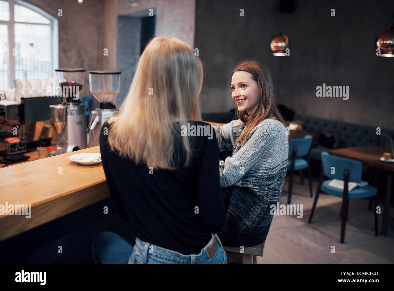 Dos amigos, disfrutando de un café juntos en una cafetería mientras se sientan en una mesa charlando Foto de stock