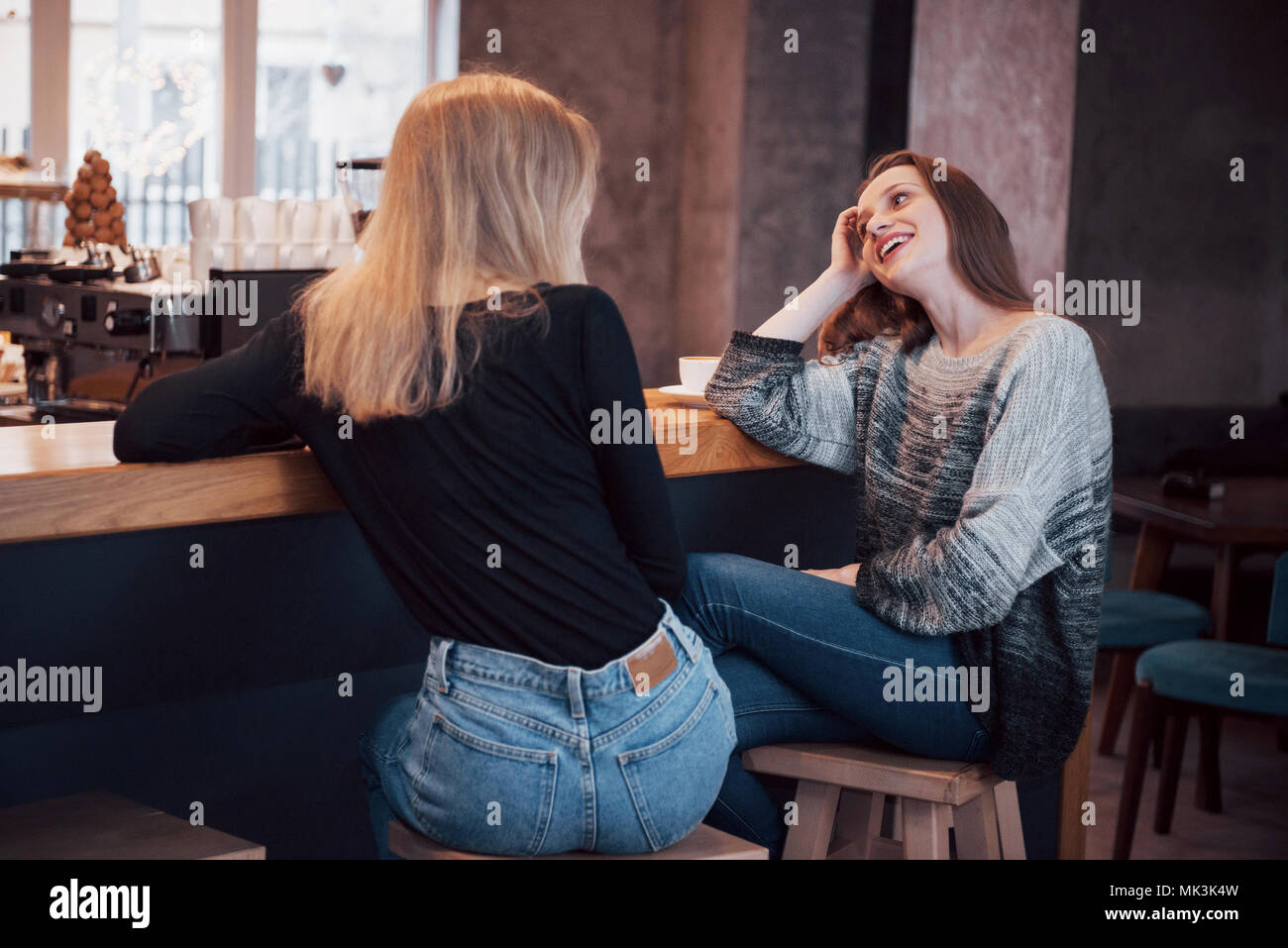 Dos amigos, disfrutando de un café juntos en una cafetería mientras se sientan en una mesa charlando Foto de stock