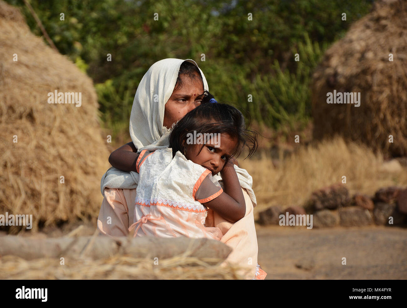 Una madre sostiene a su hijo amorosamente dándole un abrazo, zona rural de la India. Foto de stock