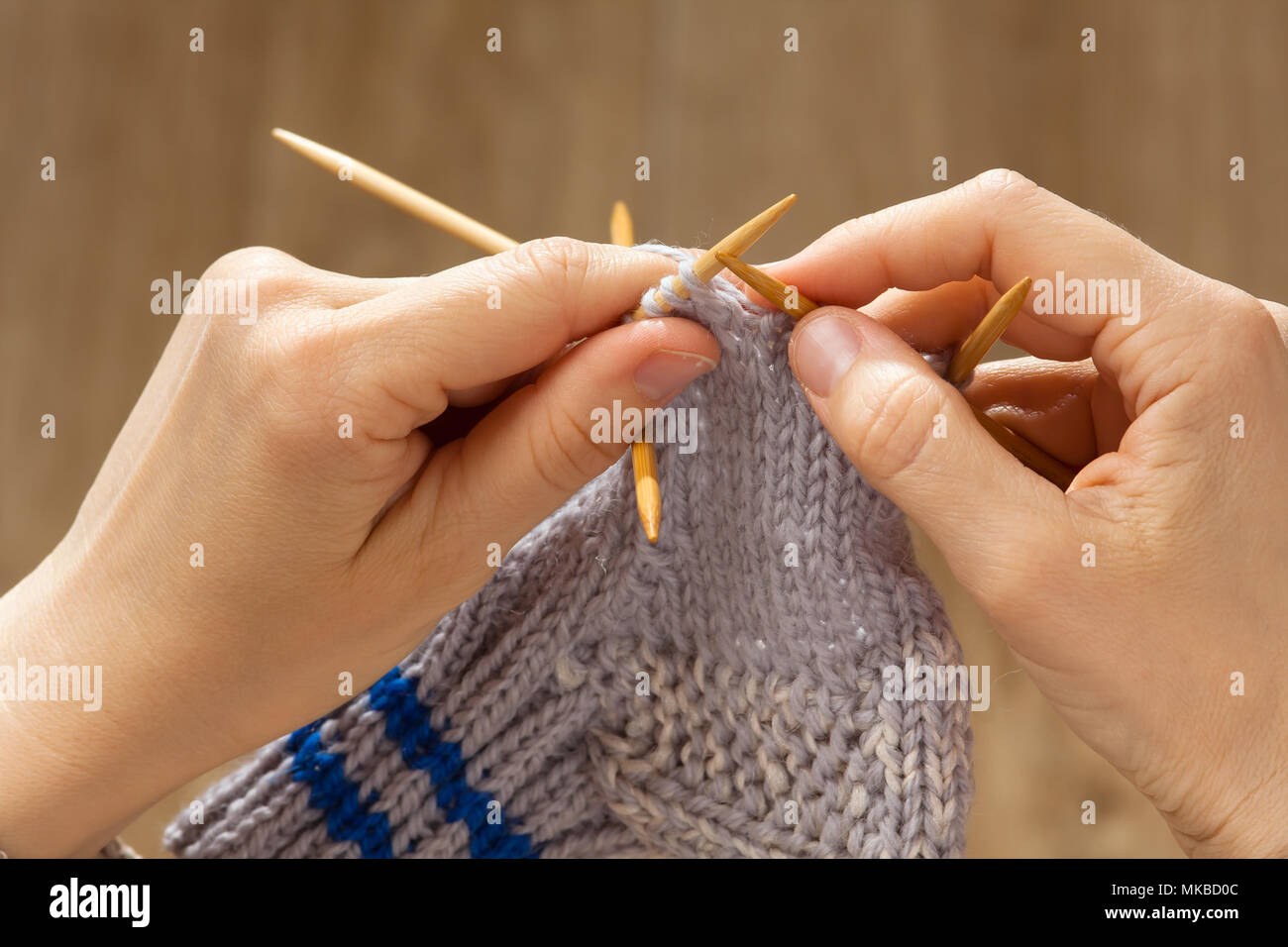 Manos de Mujer tejiendo un calcetín con agujas de bambú Foto de stock