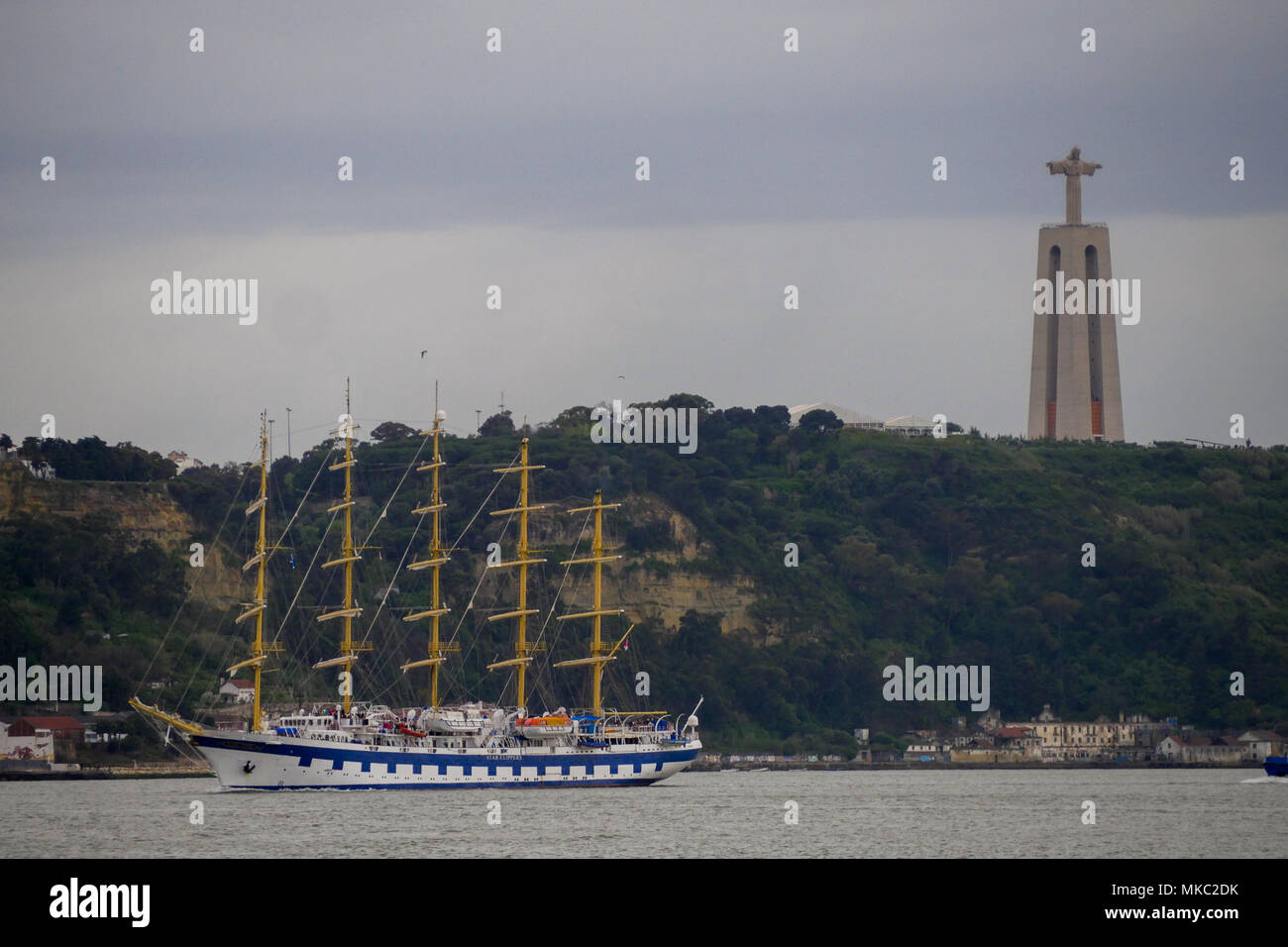 Un barco de cuatro mástiles velas ar pie de Christus Rei estatua gigante, Lisboa, Portugal Foto de stock