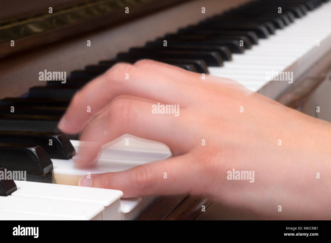 Cerca de la mano de una mujer tocando el piano con el desenfoque de movimiento Foto de stock