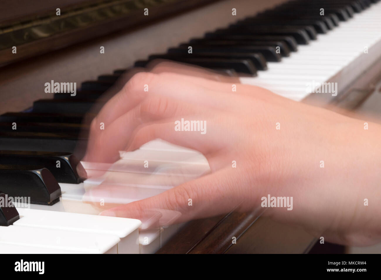 Cerca de la mano de una mujer tocando el piano con el desenfoque de movimiento Foto de stock