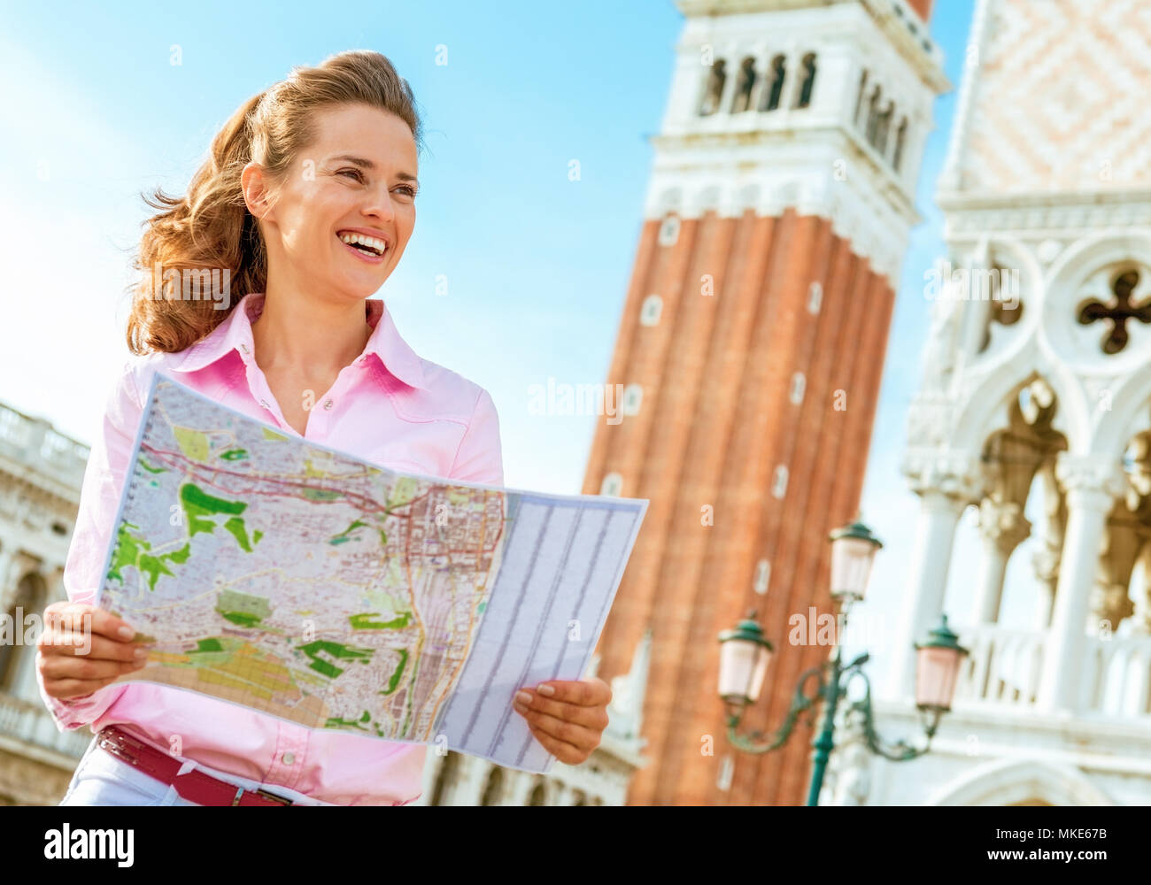Feliz joven mirando el mapa contra el Campanile di San Marco en Venecia, Italia Foto de stock