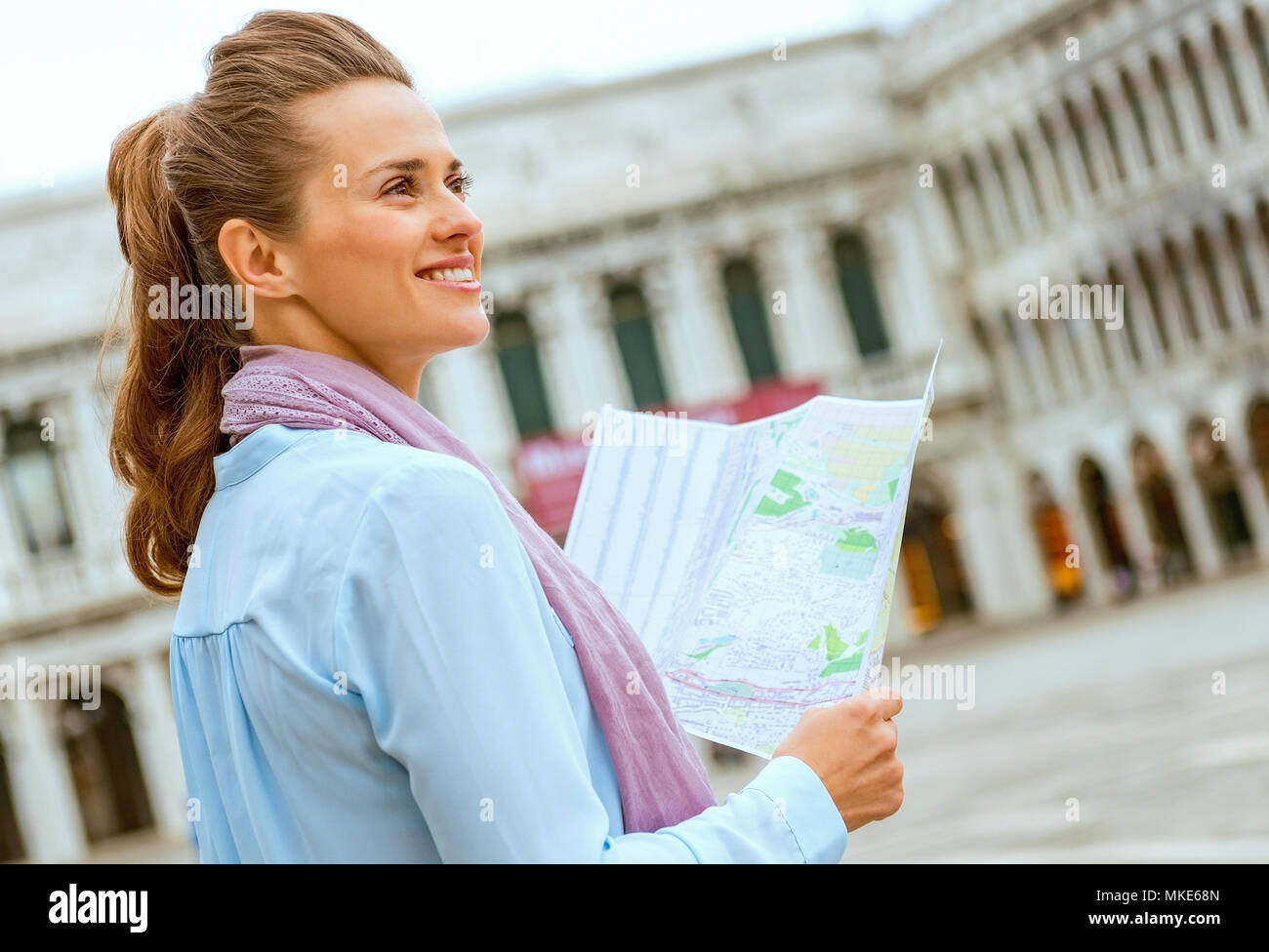 Mujer joven feliz con el mapa en la plaza de San Marcos en Venecia, Italia Foto de stock