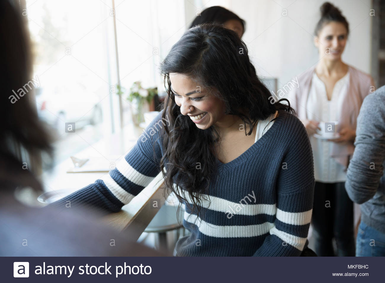 Laughing joven hablando con un amigo en el café Foto de stock