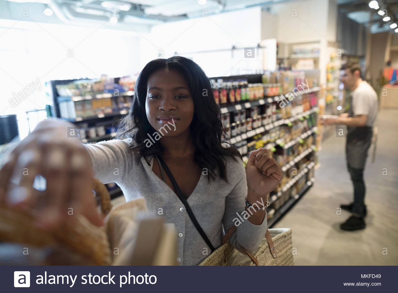 Joven, compras de supermercado, alcanzando para el pan en el mercado Foto de stock