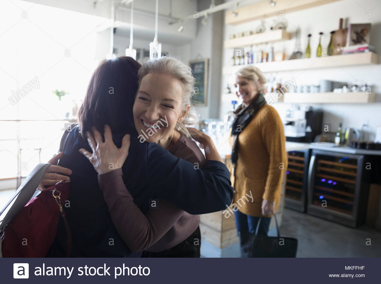 Feliz mujeres mayores amigos saludo, abrazando en cafe Foto de stock