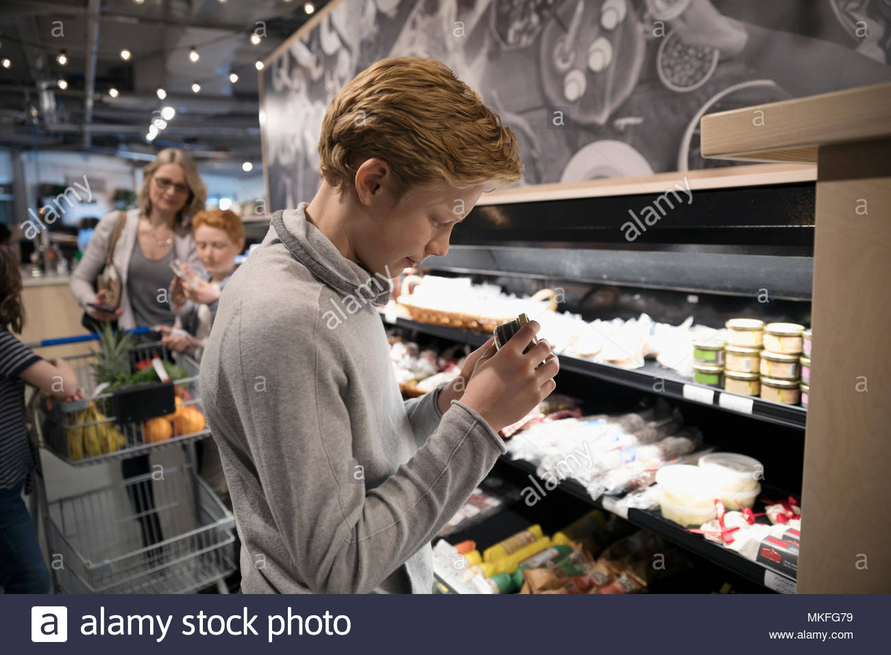 Boy compras de supermercado, mostrando el queso en el mercado Foto de stock