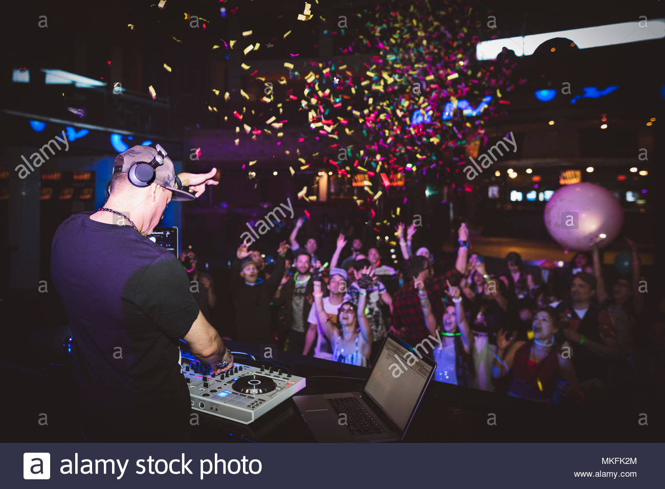 Confetti cayendo sobre DJ tocando música y gente bailando en la discoteca Foto de stock