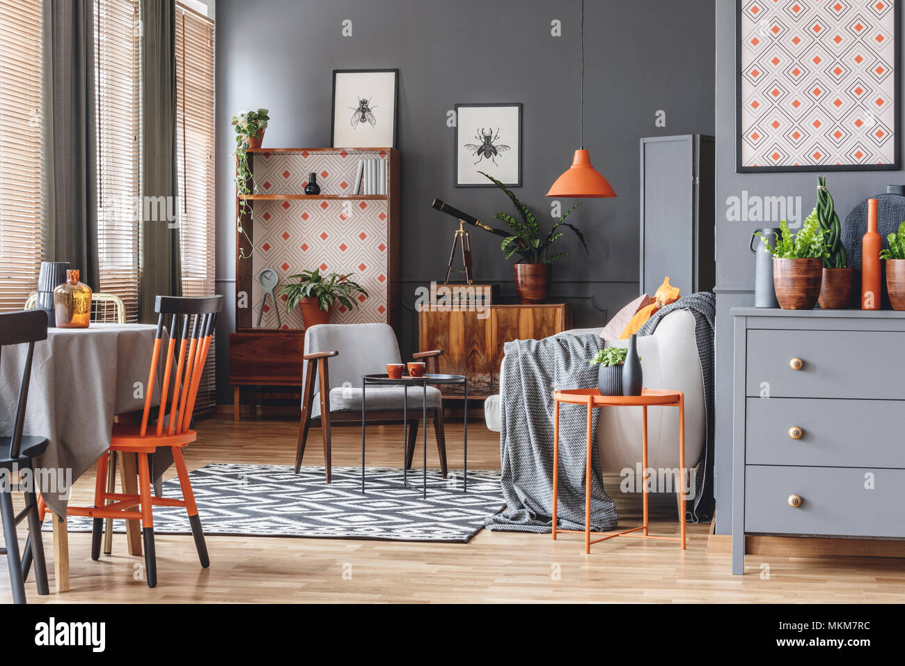 Luz naranja sobre beige sofá en gris espacio abierto interior con un sillón  y una silla en la mesa de comedor Fotografía de stock - Alamy