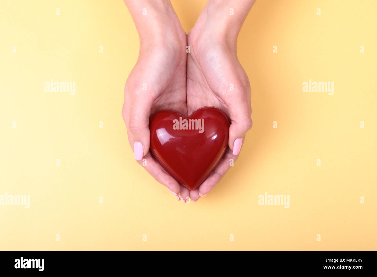 Una mujer sostiene un corazón rojo en sus manos. Foto de stock