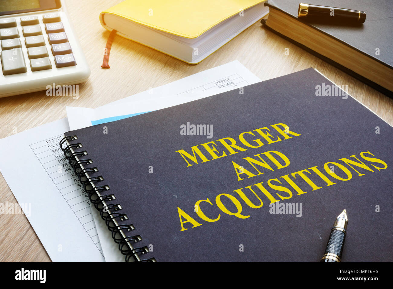 Libro sobre fusiones y adquisiciones M&A en un escritorio. Foto de stock