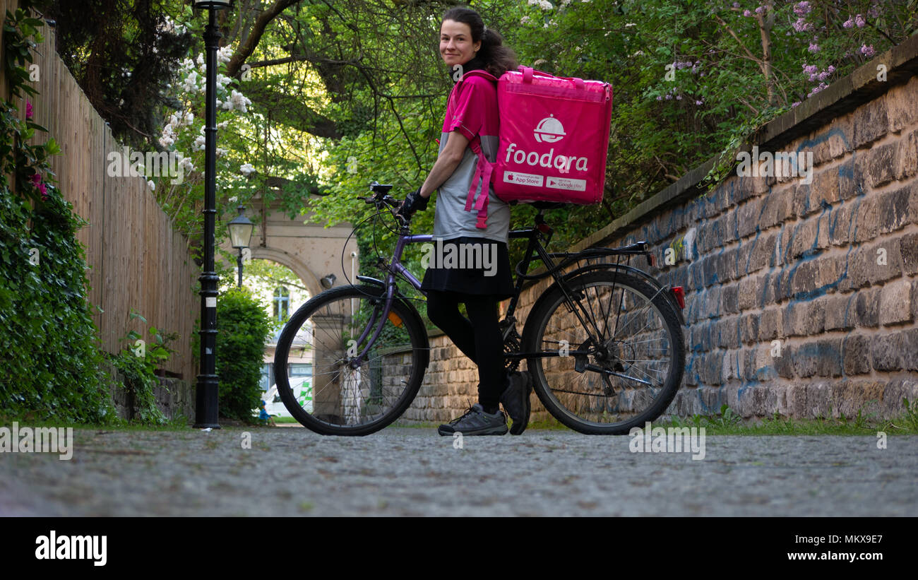 Dresden, Alemania: el servicio de entrega de alimentos. Una hembra empleado foodora caminando su bicicleta durante un descanso, posando para la cámara. Foto de stock