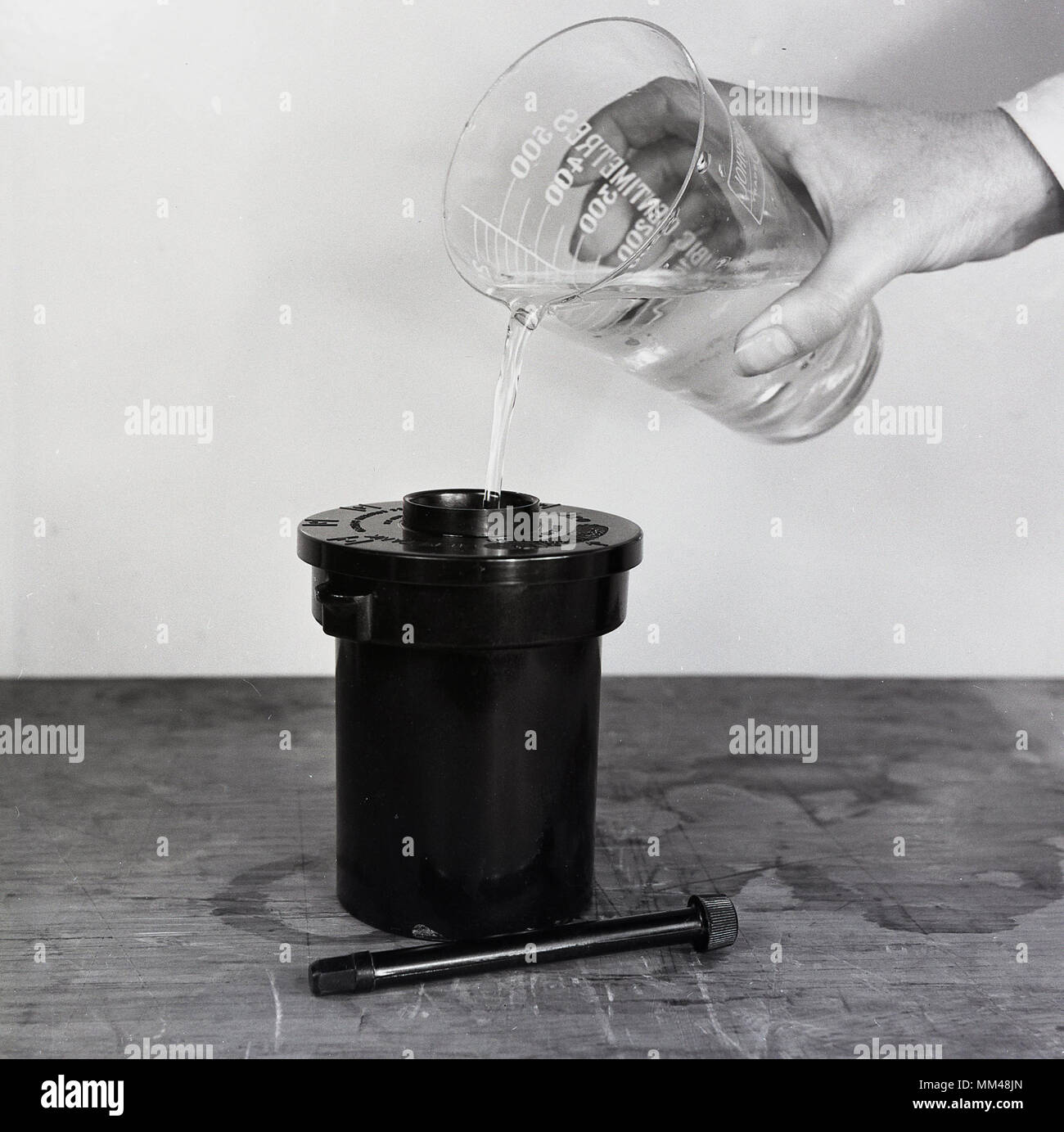 1950, foto histórica mostrando la solución química que se agrega a un recipiente para desarrollar la película fotográfica en blanco y negro. Foto de stock