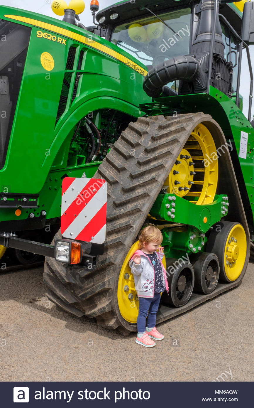 Celebrando 100 años de John Deere. John Deere 9620RX tractor de orugas, con un niño de pie junto a la oruga delantera para dar una idea de la escala Fotografía de stock -